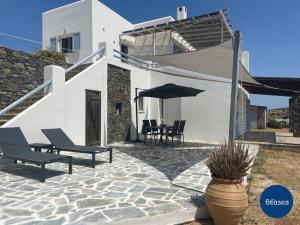 a patio with two chairs and an umbrella in front of a house at Theasea Suites - Ateliou in Vári