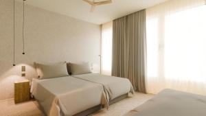 a white bedroom with two beds and a window at Hotel Taro Santa Cruz in Santa Cruz de Tenerife