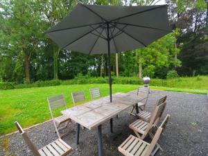 einen Holztisch mit Stühlen und einem Sonnenschirm in der Unterkunft Gite with swimming pool situated in wonderful castle grounds in Gesves in Gesves