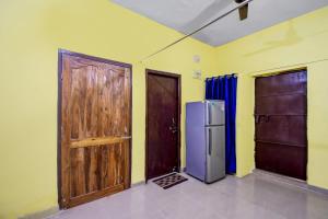 a room with two wooden doors and a refrigerator at Hotel O MO OYO in Khandagiri