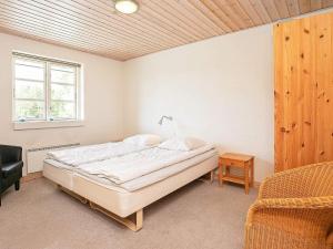 a bedroom with a bed and a chair and a window at 12 person holiday home in Hals in Hals