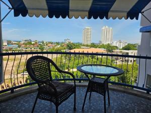 eine Terrasse mit zwei Stühlen und einem Tisch auf einem Balkon in der Unterkunft Villa Germania in Jomtien Beach