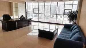 a living room with a blue couch and a large window at Binhao Hotel in Zhangguanying