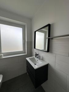 Un baño blanco con lavabo y espejo. en Star Ferien Appartement, en Otterndorf 25 fotos más