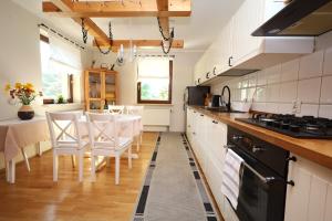 a kitchen with white cabinets and a table with chairs at Dom pod Górskim Niebem in Kobiernice