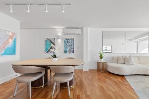 una sala da pranzo con tavolo, sedie e divano di Absolute Beachfront Luxury a Sydney