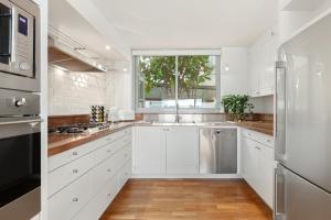 una cucina bianca con lavandino e finestra di Absolute Beachfront Luxury a Sydney