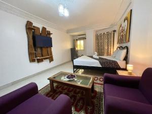 ein Hotelzimmer mit einem Bett und lila Möbeln in der Unterkunft Touraco Suite Hôtel Business in M'bour