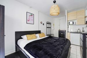 a bedroom with a large bed and a kitchen at Charming studio - 2P - Batignolles in Paris