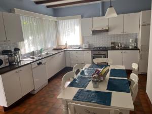a kitchen with white cabinets and a table and chairs at Parelintgroen in Kasterlee