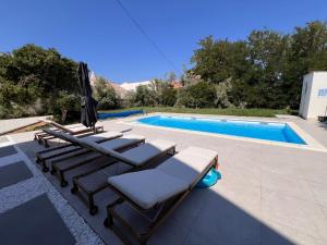 a group of lounge chairs next to a swimming pool at Villa Paro in Pag
