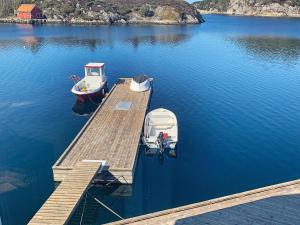 two boats are docked at a dock on a lake at 6 person holiday home in Urangsvåg in Steinsbø