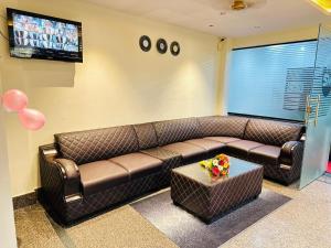 a living room with a brown leather couch and a table at Hotel SM Comforts BTM Layout in Bangalore