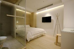 ein Schlafzimmer mit einem Bett und ein Badezimmer mit einem TV in der Unterkunft Mini West Hotel in Taichung