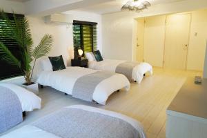 北中城村にあるVILLA fantasia Okinawa Kitanakagusukuのホテルルーム ベッド3台&ヤシの木付