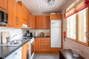Una cocina con gabinetes de madera y un refrigerador blanco. en Villa Sinirinta, Ounasvaara, en Rovaniemi