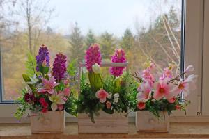 three vases filled with flowers on a window sill at Centrum Edukacji Ekologiczno-Turystycznej in Myczków