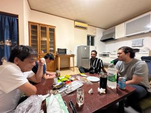 a group of people sitting around a table in a kitchen at ゲストハウス輝庵 in Sado