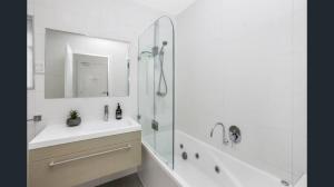 a bathroom with a sink and a shower with a mirror at Apollo Centre Apartment in Apollo Bay +8 photos