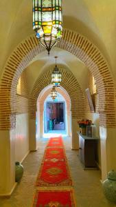 a hallway with a red carpet and a chandelier at Riad El Hara in Marrakech