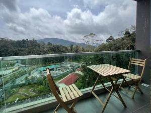a balcony with two chairs and a table and a view at Barakah Sufi Home Stay Apartment Cameron in Tanah Rata