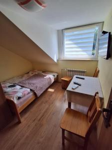 a bedroom with a bed and a table and a window at Agroturystyka Pod Brzozami in Susiec