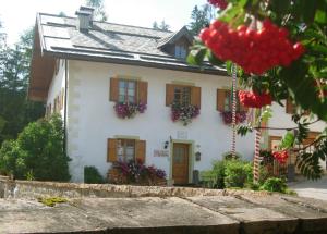 a white house with flowers in front of it at Achillea Bed & Breakfast in Vigo di Fassa