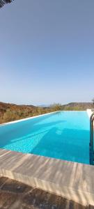 a large blue swimming pool with the ocean in the background at Cortijo J&S Juan Salvador in Málaga