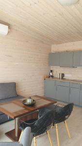 a living room with a wooden table and a kitchen at Vieno aukšto kotedžas in Šventoji