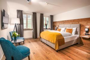 a bedroom with a bed and a blue chair at Terofal Hotel Schliersee - Komplett neu renoviert in Schliersee