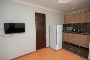 a kitchen with a refrigerator and a tv on a wall at HOTEL COSMOS in Batumi