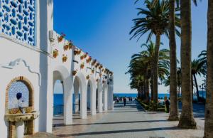 a walkway next to the beach with palm trees at Coco Stay Nerja in Nerja