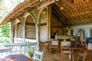 a restaurant with wooden tables and chairs and a patio at Aga Surf View in Tangalle