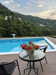 a table with a vase of flowers on it next to a pool at Villa Oranji in Itʼkhvisi