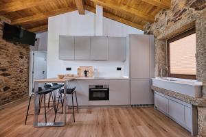 a kitchen with white cabinets and a table with stools at As casiñas da Figueira by Serendipia Turismo in Pobra do Caramiñal