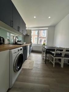una cucina con lavatrice e tavolo con sedie di Appartement de luxe Dubai , Chambre, salon et SDB Privés, cuisine partagée a Liegi