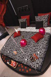 a black and white bed with red pillows on it at Love room - L'escapade du désir in Trouillas