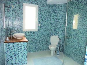 La salle de bains est pourvue de carrelage bleu, de toilettes et d'un lavabo. dans l'établissement Villa moderne à 200m de la mer avec jardin clos, à Saint-Vaast-la-Hougue