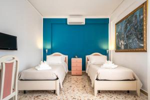 two beds in a room with a blue wall at Centoquaranta Apartment in Terrasini