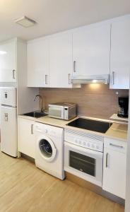 a kitchen with white cabinets and a microwave and a dishwasher at Parque Playa II in Gijón +14 photos