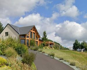 une maison en rondins avec une route sinueuse dans l'établissement Le Cocon des Volcans d'Auvergne, à La Chapelle-dʼAlagnon