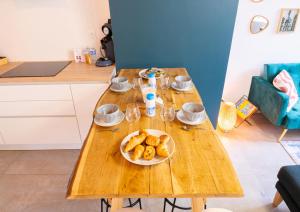 a wooden table with a plate of bagels on it at Le Carnot - Petit DEJ - Hyper-centre BY PRIMO in Mâcon
