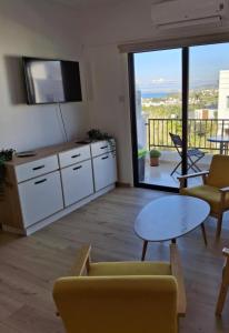 ein Wohnzimmer mit einem Tisch und Stühlen sowie einem großen Fenster in der Unterkunft Apartment with sea view! in Klorakas