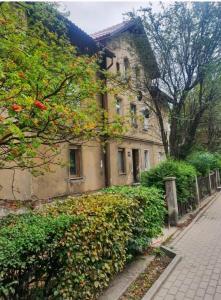 an old building with a hedge next to a street at Apartamenty Biały Kamień in Wałbrzych
