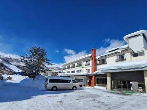 a van parked in a parking lot in front of a building at Summit Views Hakuba in Hakuba
