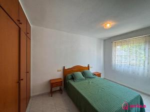 - une chambre avec un lit doté d'une couette verte et d'une fenêtre dans l'établissement El Bungalow, à Oropesa del Mar