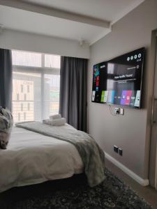 a bedroom with a bed with a flat screen tv on the wall at Menlyn Maine Trilogy Apartment 519 in Pretoria