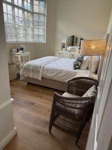 a bedroom with a bed and a chair and window at Railway Cottage at Rawdons Country Estate in Nottingham Road