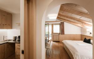 a bedroom with a large bed and a kitchen at Residence Sovara in Santa Cristina in Val Gardena