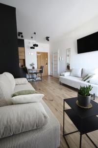 Una sala de estar con dos sofás blancos y una mesa. en Apartament LUX, en Zator